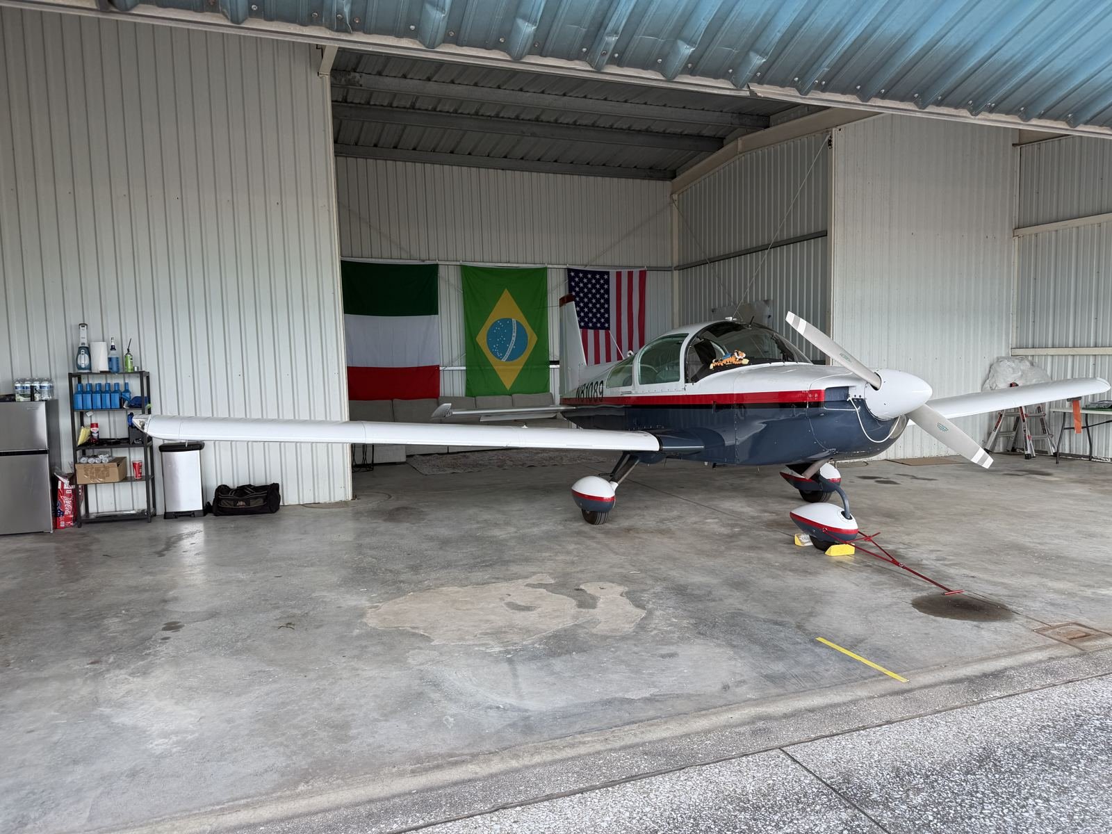 N81089 parked in the hangar next to Italian, Brazilian, and American flags